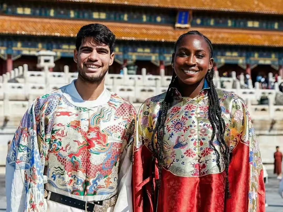 Travellers in traditional indian outfits look at Taj Mahal in the distance while standing close